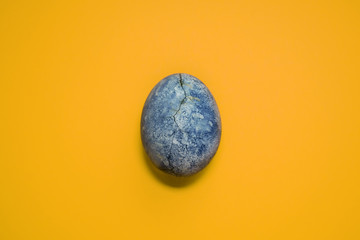 Blue egg with crack, painted in tea hibiscus, on orange background, similar to dragon eggs and marble with copyspace