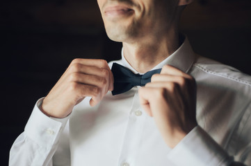 Portrait of Handsome groom getting dressed in a wedding shirt. 