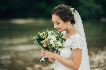 Beautiful Bride with hairstyle and makeup posing with Wedding Bouquet.