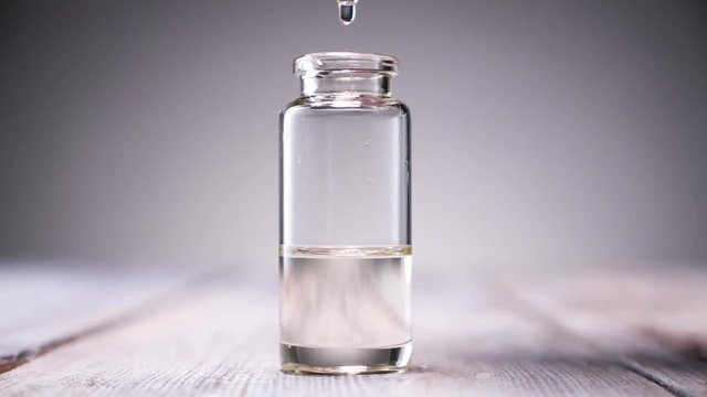 Blend of essential oils. Making some aroma liquids, perfume. Drops falling from pippet to little glass bottle. Slowmotion.