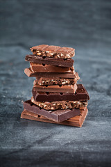 Chocolate bar pieces stack on black background. Sweet food photo concept.