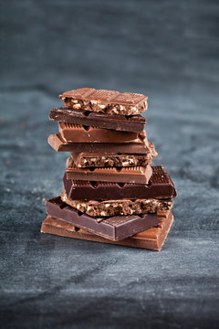 Chocolate bar pieces stack on black background. Sweet food photo concept.