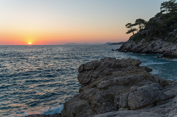 A sun sets over the horizon and illuminates the Mediterranean sea and mountains; Colorful seascape. The sea at sunset