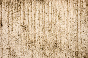 Beige weathered rough surface of a plastered wall with dirty streaks from flowing water