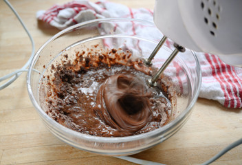 electric mixer in action stirring dough for chocolate cake in a glass bowl, motion blur, baking concept