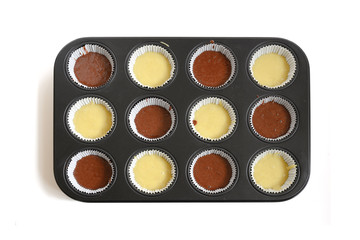 muffin baking tray filled with two kinds of cake dough for delicious cupcakes, high angle view from...