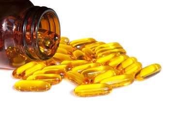 Fish oil gel capsules with omega 3 and vitamin D in brown glass bottle isolated on white...