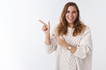 Gorgeous talkative charming female designer showing friend new products smiling broadly persuading buy pointing left grinning amused delighted having fun promoting advertisement, white background