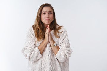 Girl acting silly miserable supplicating pressing palms together pray pursing lips asking please help lend money begging favour lookg cute poor kitten, standing white loose sweater studio background
