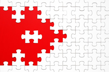 White puzzle pieces on a red background separated