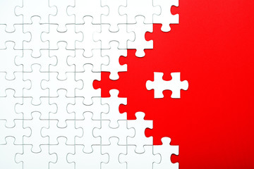 White puzzle pieces on a red background separated