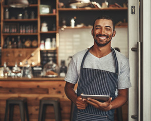 Portrait of a male owner holding digital tablet in his cafe