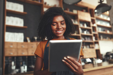 Fototapeta premium Portrait of an african female cafe owner using digital tablet