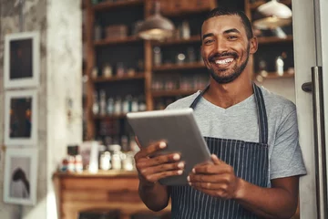 Rolgordijnen Smiling male cafe owner holding digital tablet in his hand © StratfordProductions