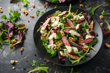 Grilled Beef Steak salad with pears, walnuts and greens vegetables and blue cheese sauce. healthy food.