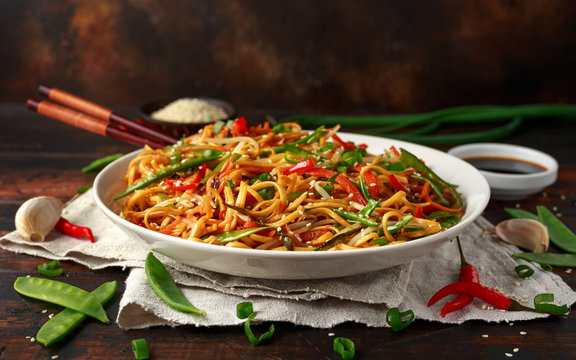 Chow mein, noodles and vegetables dish with wooden chopsticks