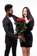 They are as beautiful as you. Full length of indian man giving a bouquet of red roses for his asian woman isolated on white background