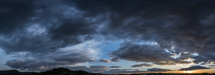 Fototapeta na wymiar Dunkle Regenwolken bei Sonnenuntergang - Panorama