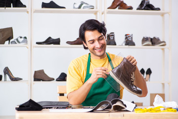 Young man repairing shoes in workshop 