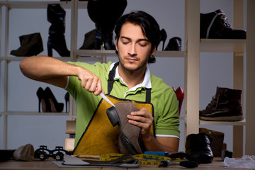 Young shoemaker in workshop at night 