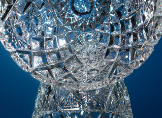 Close up view of glowing crystal glass, abstract background. Detail of vintage vase design. Beautiful blue macro view of glittering light refraction in cut glass facets.