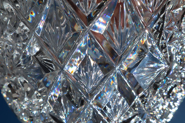 Close up view of glowing crystal glass, abstract background. Detail of vintage vase design. Beautiful blue macro view of glittering light refraction in cut glass facets.