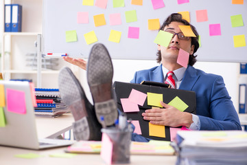Young male handsome employee in conflicting priorities concept 