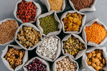 Top view of healthy dry ingredients in burlap bags. Nutritious cereals and dried fruit: almond, garbanzo, pistache, goji, buckwheat, mulberry, legume in cloth sacks