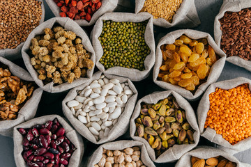Colourful various beans in cloth sacks. Uncooked assorted legumes. Mulberry, buckwheat, pistache, raisins, almond, garbanzo, others. Healthy cereals.
