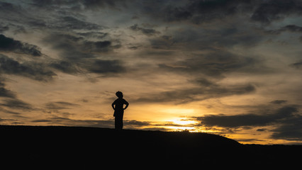 Senior female traveller standing against sunset