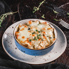 Casserole with cheese, broccoli, cauliflower and herbs in bowl over dark background with napkin. Healthy dinner or lunch setting, clean eating, closeup