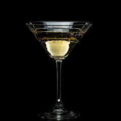 in a martini glass, vermouth ice falls, and splashes with drops on a black background