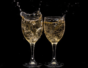 Two crystal wine glasses with a drink, falling ice and splashes
