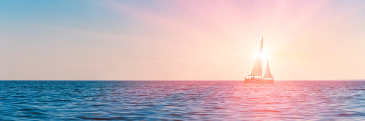 Banner 3:1. Sailboat in the sea in the evening sunlight over sky background. Luxury summer...