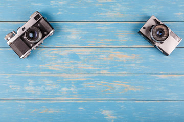 Two old cameras on a blue wooden background