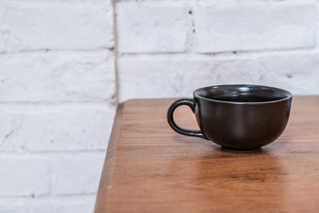A black cup of coffee in coffee shop. on wooden table