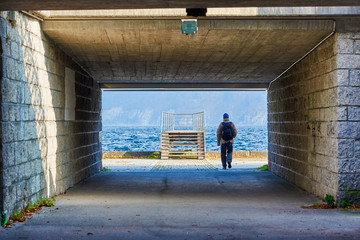 Obraz na płótnie Canvas Man with a backpack goes to the pier. Mountain lake Traunsee in Austria, Salzkammergut region.