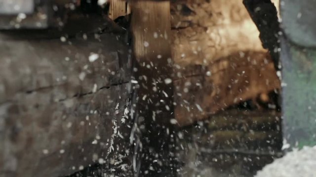 production of wooden lumber and planks. A sawmill blade saws a log into planks. sawdust flying slow motion