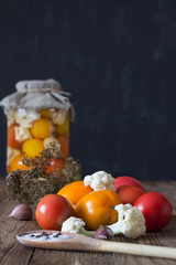 Preparation of fermented vegetables. Fresh tomatoes,cauliflower,spices in the foreground. Dark background. Copy space