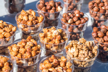 A variety of nuts in plastic bowls in the outdoor market
