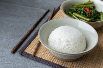 Fried morning glory with rice in gray bowl on table.