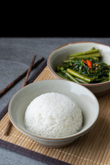 Fried morning glory with rice in gray bowl on table.