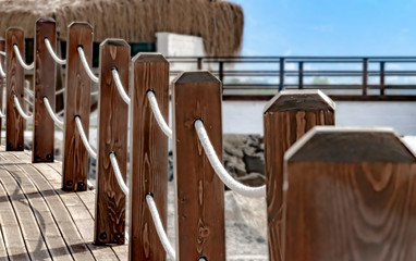 Fototapeta na wymiar Pedestrian bridge along the coast with a fence with a rope. Sea summer landscape.