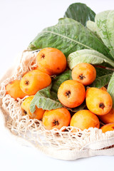 Loquat fruit.  Eriobotrya Japonica. Loquat with fresh leaves on background