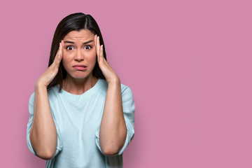 Isolated facial expression of a worried, concerned, fearful, regretful woman, expressing distress and inner conflict, pink background - 268522721