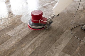 Cleaning machine drives over the tiled floor and cleans the floor.