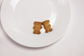 Cute bears cookies on the ceramic round plate isolated on white background. View from above, flat lay.