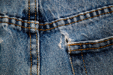 back side of double sewn seams and frayed hole on pocket of old blue jeans