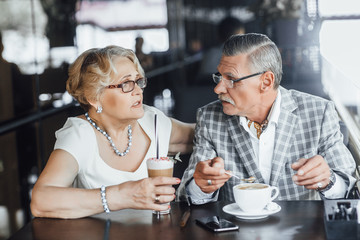 Breakfast with a loved one, elderly men and women drink together latte, being at summer terrace at cafe