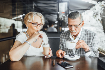 Senior couple interacting while having coffee in cafe at summer terrace,and drinking latte